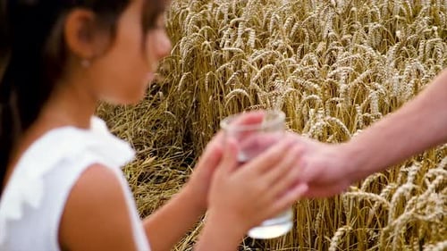 Father Offers Refreshing Water to His Daughter in Field
