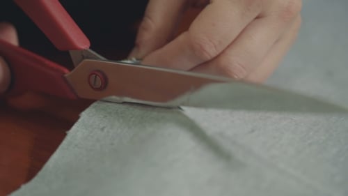 Hands Cutting Material With Scissors in Close Up