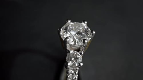 Extrem detaillierte Nahaufnahme des Diamantrings beim Drehen auf dunklem Hintergrund