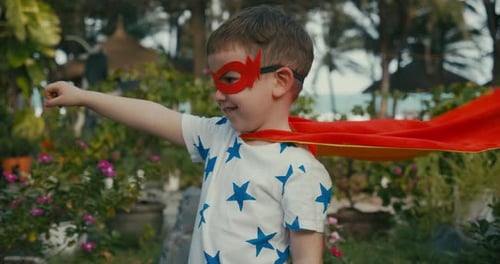 Boy Pretends to be Superhero in Tropical Garden