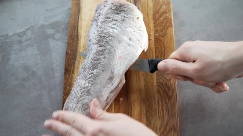Preparing Fish with Knife on Wood Cutting Board