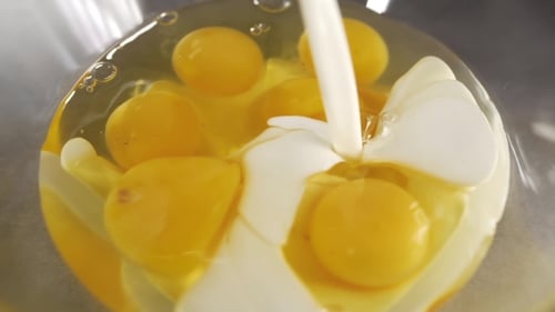 Cream Being Poured into Bowl of Raw Egg Yolks