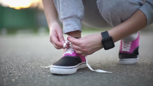 Young Adult Tying Sneaker Laces at Sunset