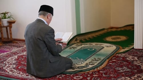 Un vieux mollah priant avec le Coran entre les mains
