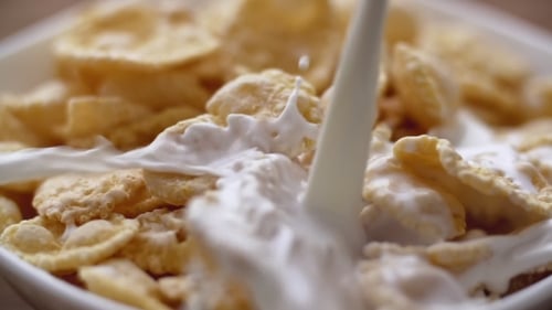 Milk Pouring Over Crispy Cornflakes Cereal in Bowl