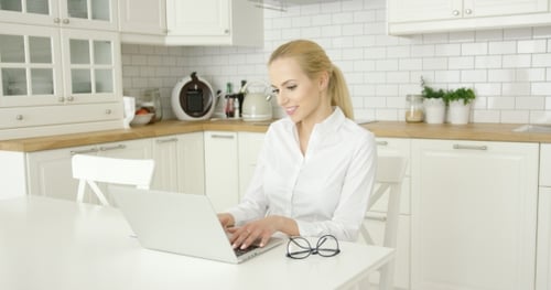 Woman Using Laptop at Kitchen Table