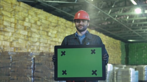 Smiling Warehouse Worker with Chromakey Sign