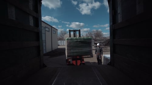 Forklift Loading Materials Into a Truck at Warehouse