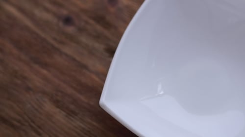 Corn Flakes Being Poured into White Bowl