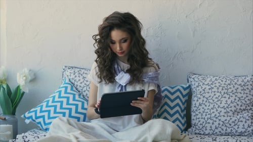 Woman Using Tablet Relaxing in Bed