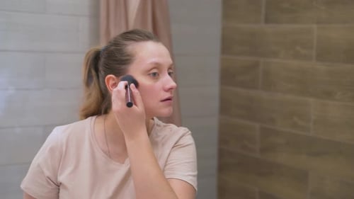 Woman Applying Makeup with Brush in Bathroom