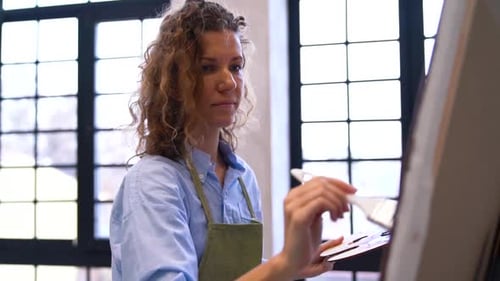 Female Artist Painting at Easel in Art Studio