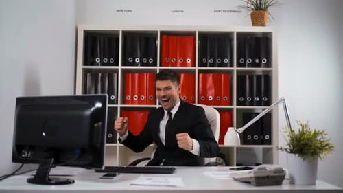Excited Man Celebrates Good News at Office Desk