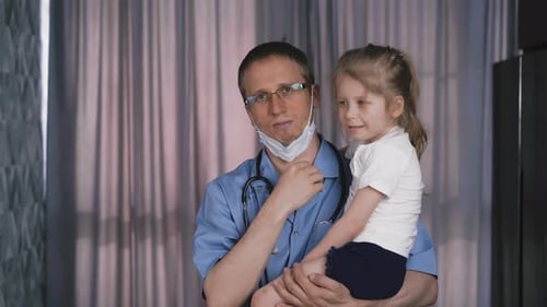 Doctor Holding a Smiling Child in Hospital Room