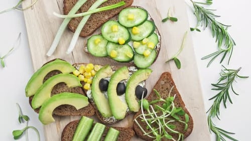 Sandwich with Avocado Cucumber Olives and Green Onions on a Wooden Board