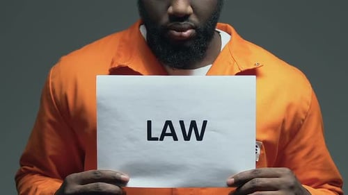 Law Word on Cardboard in Hands of Black Prisoner, Order and Justice Demanding
