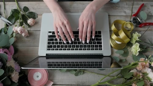 A Woman Is Working By Using a Laptop Computer on Table. Hands Typing on a Keyboard. Flower Shop
