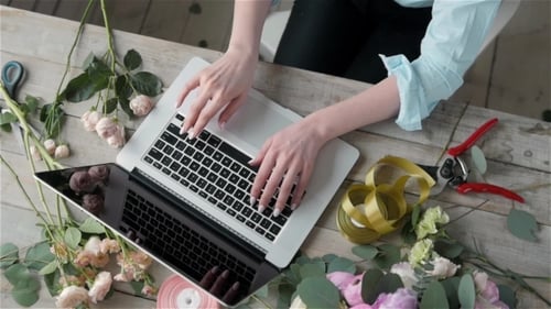 Office Workplace Essentials: Laptop, Paper Notebook, Bouquet of Flowers on the Rustic Wooden Table