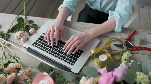 A Woman Is Working By Using a Laptop Computer on Table. Hands Typing on a Keyboard. Flower Shop