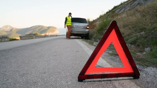 A Man Walks Next To a Broken Car Waiting for Help