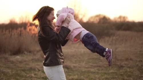 Mother and Child Playing at Sunset in Rural Field