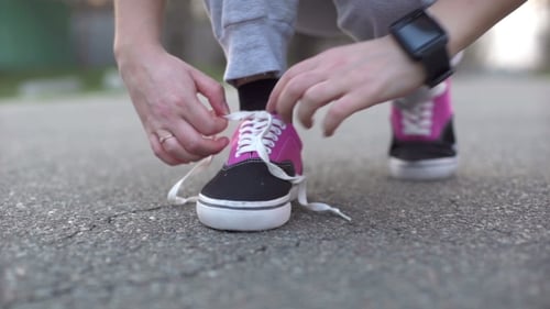 Woman Tying Athletic Shoe Laces on City Street