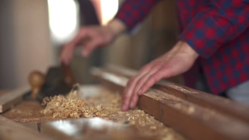 Der Zimmermann fegt die Späne mit Holz vom Holz.