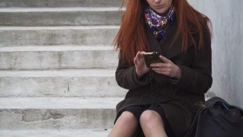Woman Sits on Steps Using Her Mobile Phone