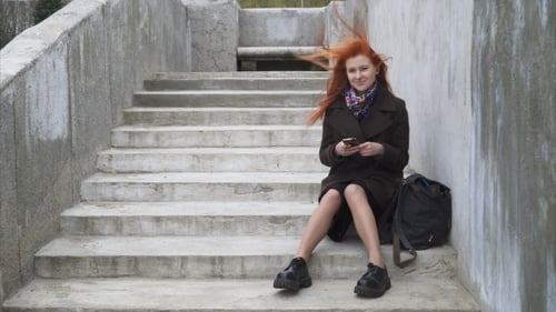 Woman With Red Hair Using Phone on Stairs