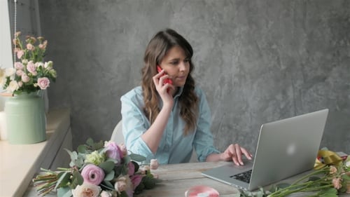 Woman Talks on Phone and Uses Laptop with Flowers