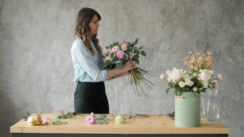 Woman Arranging Elegant Flower Bouquet at Table