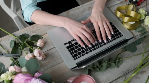 Office Workplace Essentials: Laptop, Paper Notebook, Bouquet of Flowers on the Rustic Wooden Table