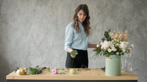 Concept de personnes, d'affaires, de vente et de fleuriste - Femme fleuriste souriante heureuse faisant un bouquet à la fleur