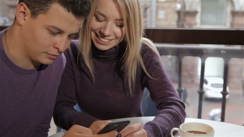Couple Looks at the Man's Smartphone Cafe