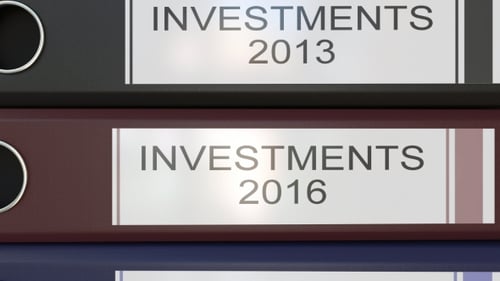 Vertical Stack of Multicolor Office Binders with Investments Tags Different Years