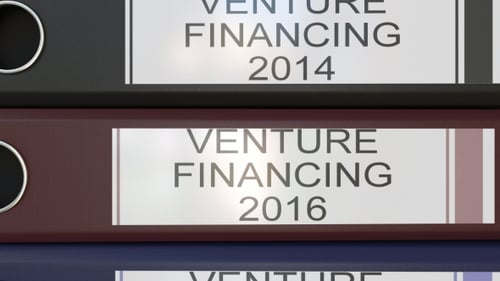 Vertical Stack of Multicolor Office Binders with Venture Financing Tags Different Years