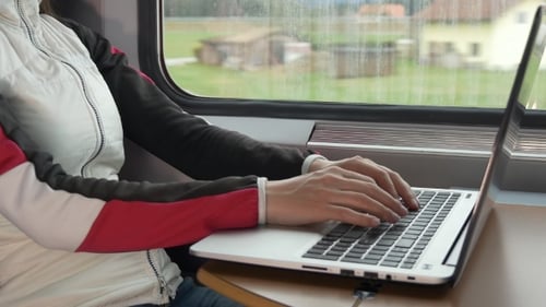 Hände auf der Laptoptastatur in der Nähe des Fensters im Zug
