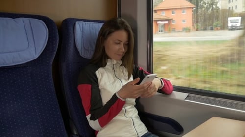 Frau tippt SMS auf dem Handy in einem Zug
