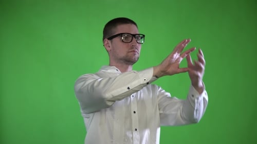 Ein strukturierter Mann mit Borsten und Brille steuert seine Hände mit einem Hologramm auf grünem Hintergrund