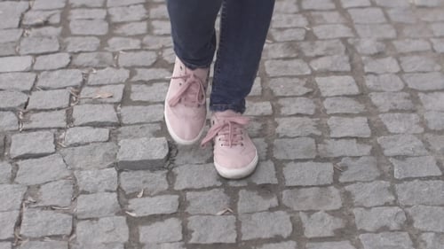 Girls Feet in Sneakers Walking on the Sidewalk