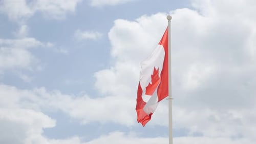 Canadian Flag Waving Against Blue Sky