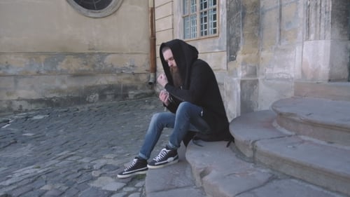 Man Sitting on Steps of a Stone Building