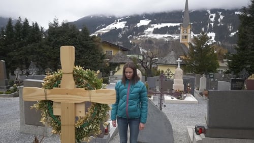 Traurige Frau auf dem Friedhof am Grab