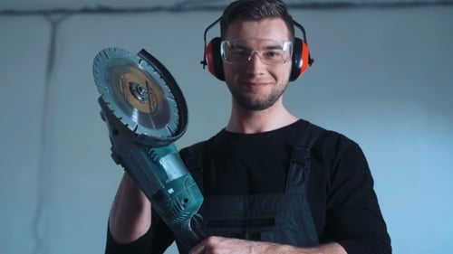 Lachender Bauarbeiter mit Winkelschleifer