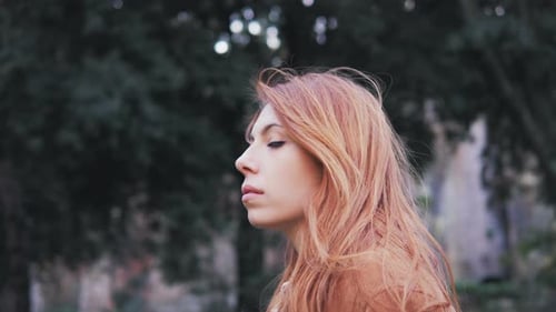 confident serious red haired young woman turning and looking at camera-outdoor