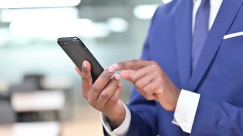 Homme d'affaires africain utilisant la messagerie texte sur smartphone