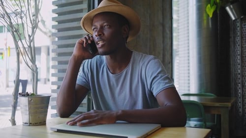 Young Black Man Sits in a Trendy Cafe