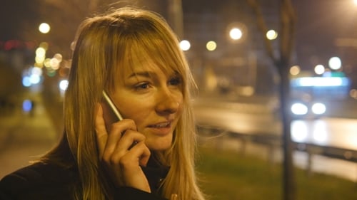 Junge Frau telefoniert abends im Freien