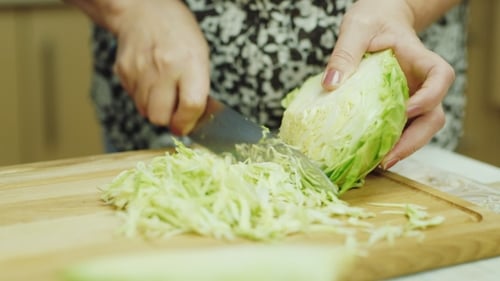 of the Hands of an Elderly Woman. Slices Cabbage for Salad
