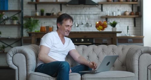 Man Video Calling on Laptop From Home Couch